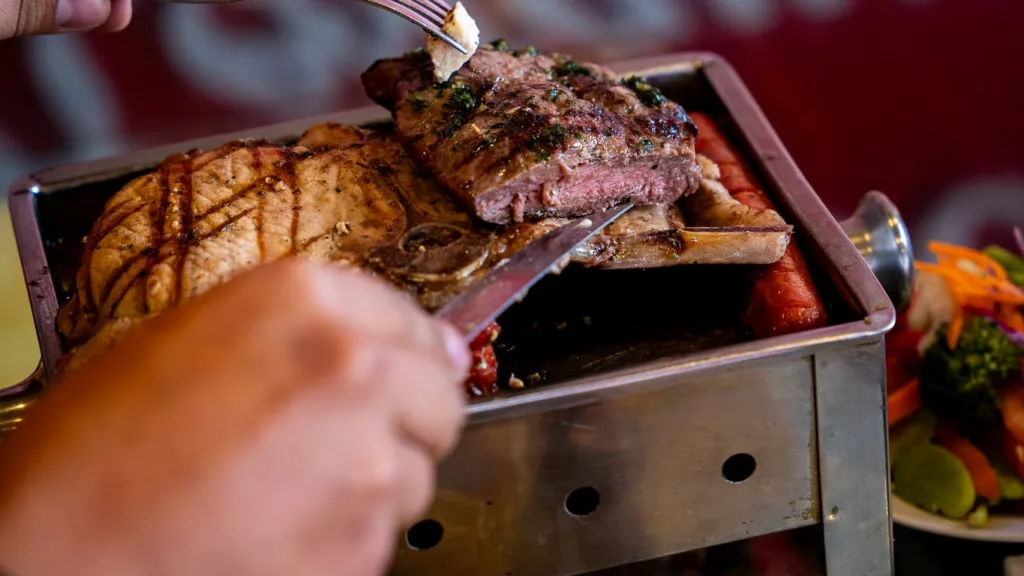 Sirviendo cortes de la parrilla de mesa en Águeda Restaurant